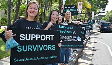 People wearing denim and waving signs in support of Sexual Assault Awareness Month.