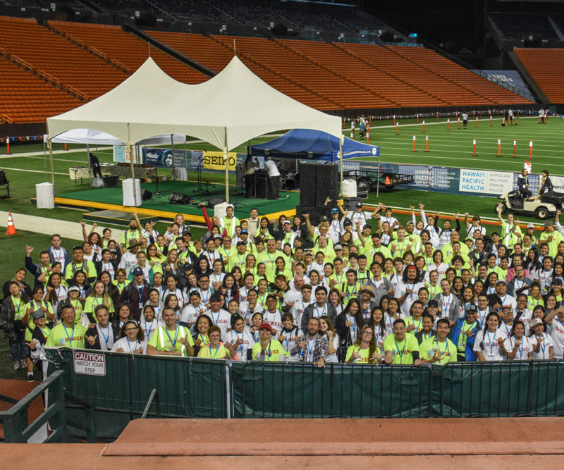Volunteers gather on the field of Aloha Stadium for a safety brief before the start of the Great Aloha Run