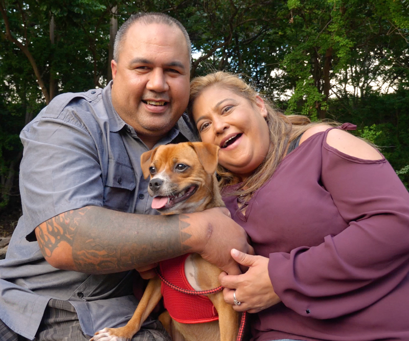 Charlyn Esera and fiance Chad sit together hugging with their small brown dog, Honey Girl, between them