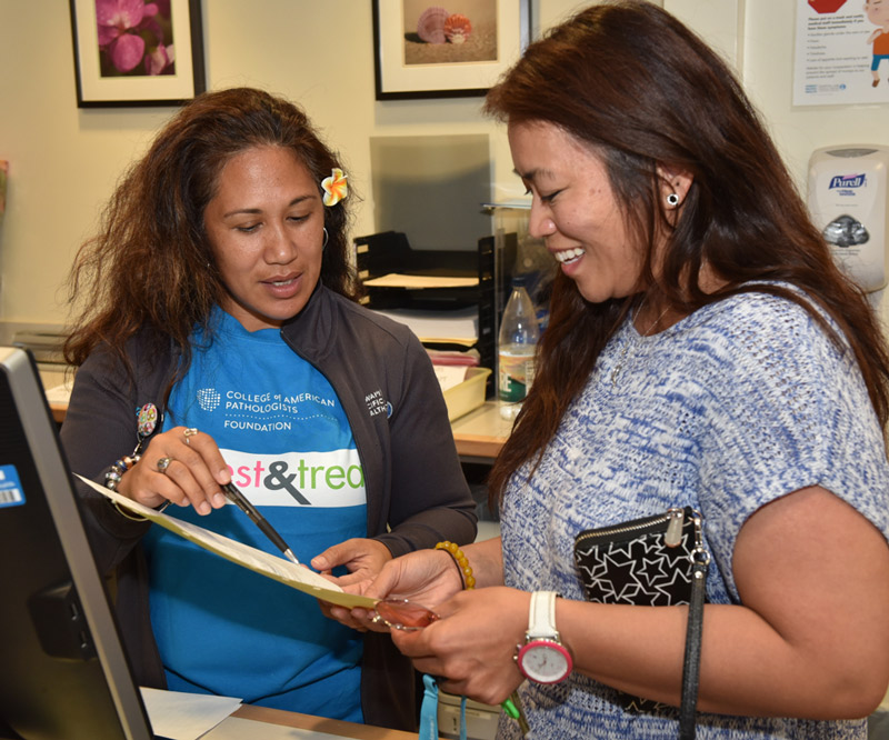 Aida Corpuz (right) reviews paperwork prior to receiving free cervical cancer and breast cancer screenings at the Kapiolani Women's Center as part of an event put on through a grant from College of American Pathologists (CAP) Foundation's See, Test & Treat program.