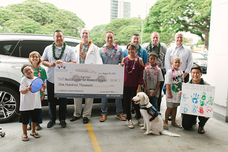 Pediatric cancer patients, Kapiolani's Dr. Darryl Glaser and Hyundai Hawaii auto dealer representatives with ceremonial check for $100,000
