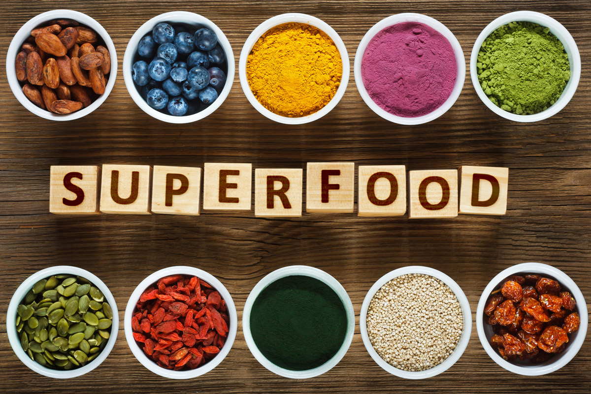 the word Superfoods spelled out in blocks surrounded by measuring cups of popular superfoods and supplements