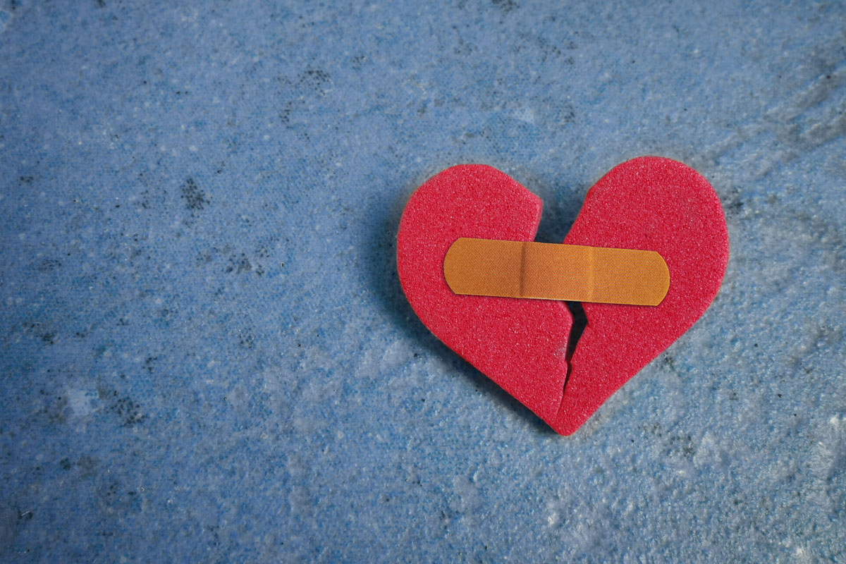 ripped paper heart held together with a band aid