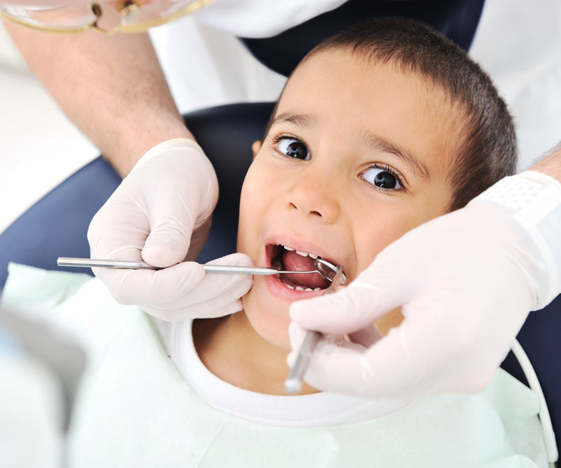 a young child with dental tools in the mouth