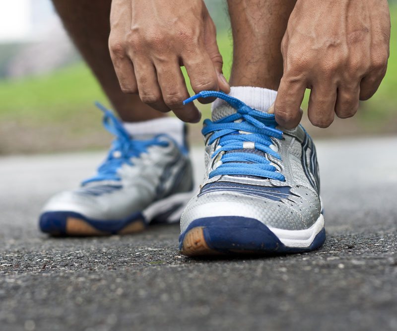 a close up of a runner adjusting their shoes