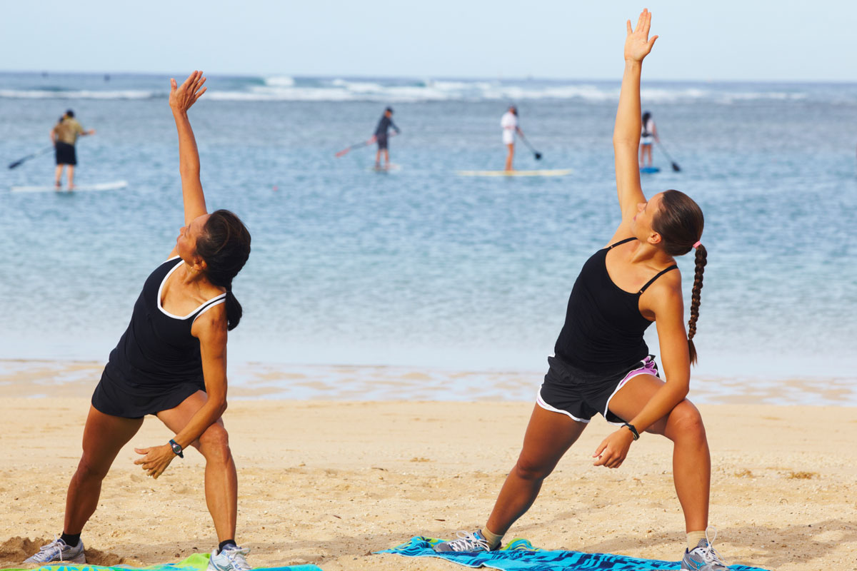 two people on the beach doing yoga