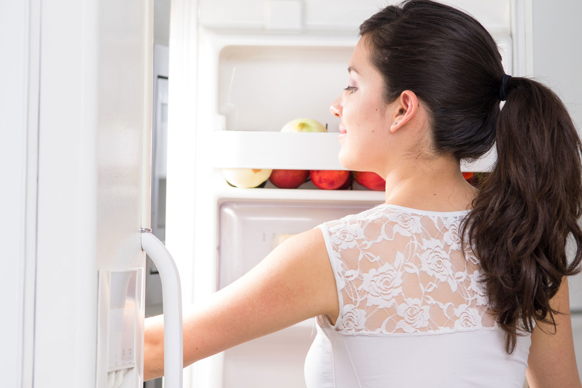 a lady looking inside a refrigerator