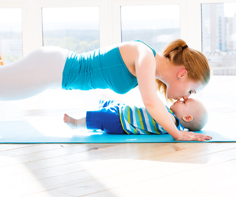 mom doing push-ups while kissing a baby