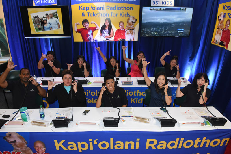 group of kids sitting at a table answering phones for a radiothon