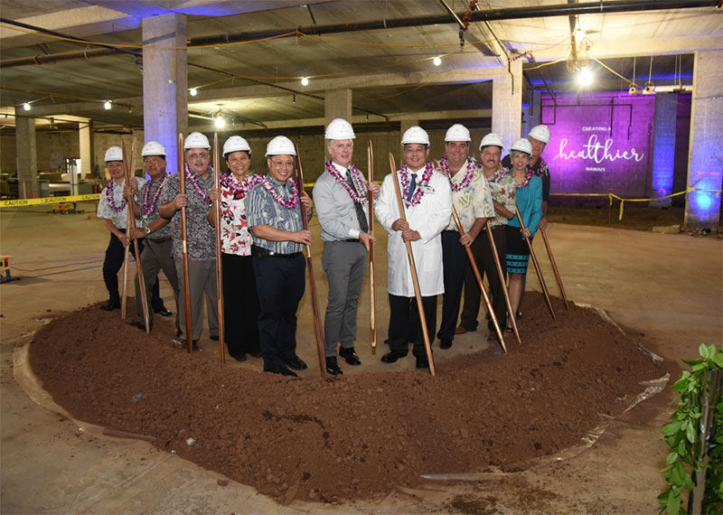 a group at a groundbreaking with shovels standing near a large mound of dirt