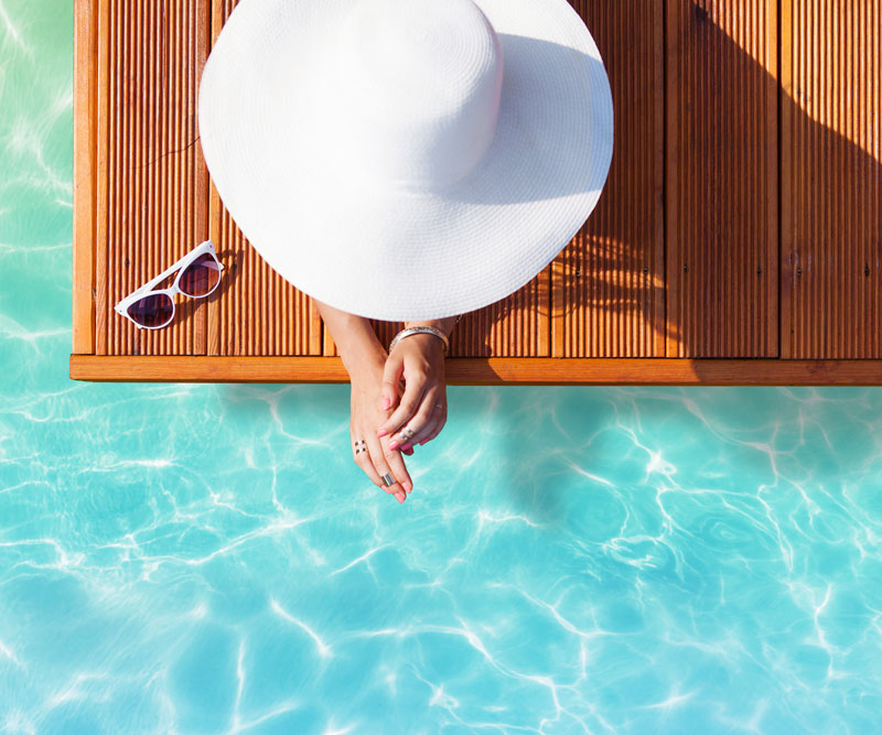 woman with sunhat sitting by the pool