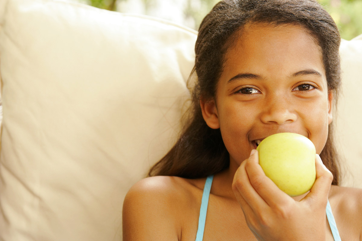 young girl taking a bite out of an apple