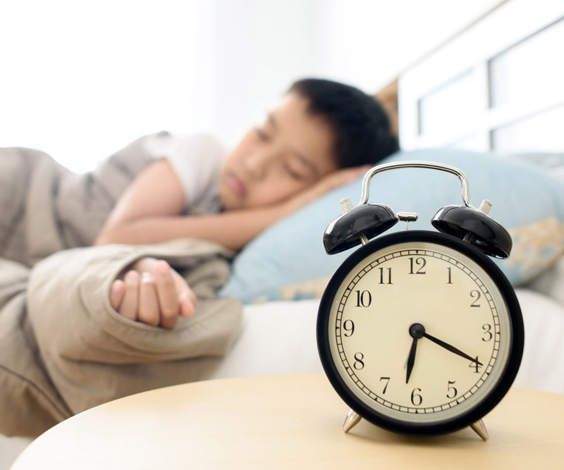 child sleeping near alarm clock