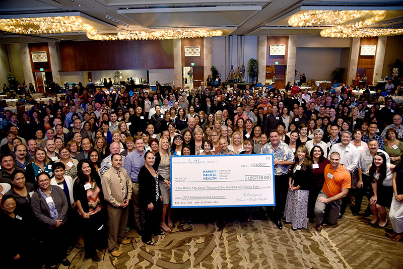 a very large group of people holding up a donation check