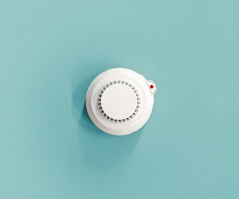 an overhead view of a smoke detector mounted on a teal ceiling