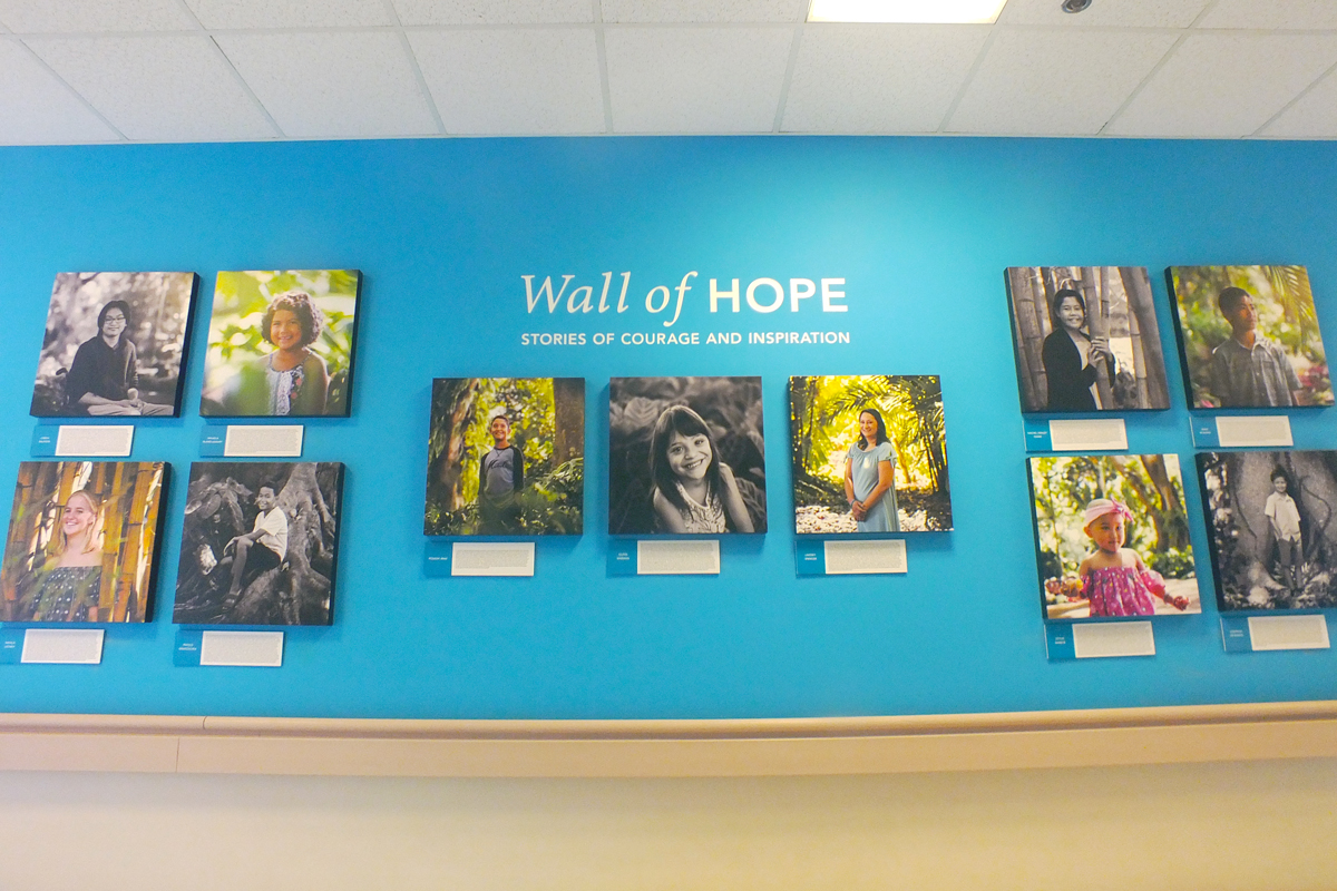 A blue wall displays images and stories of former patients.