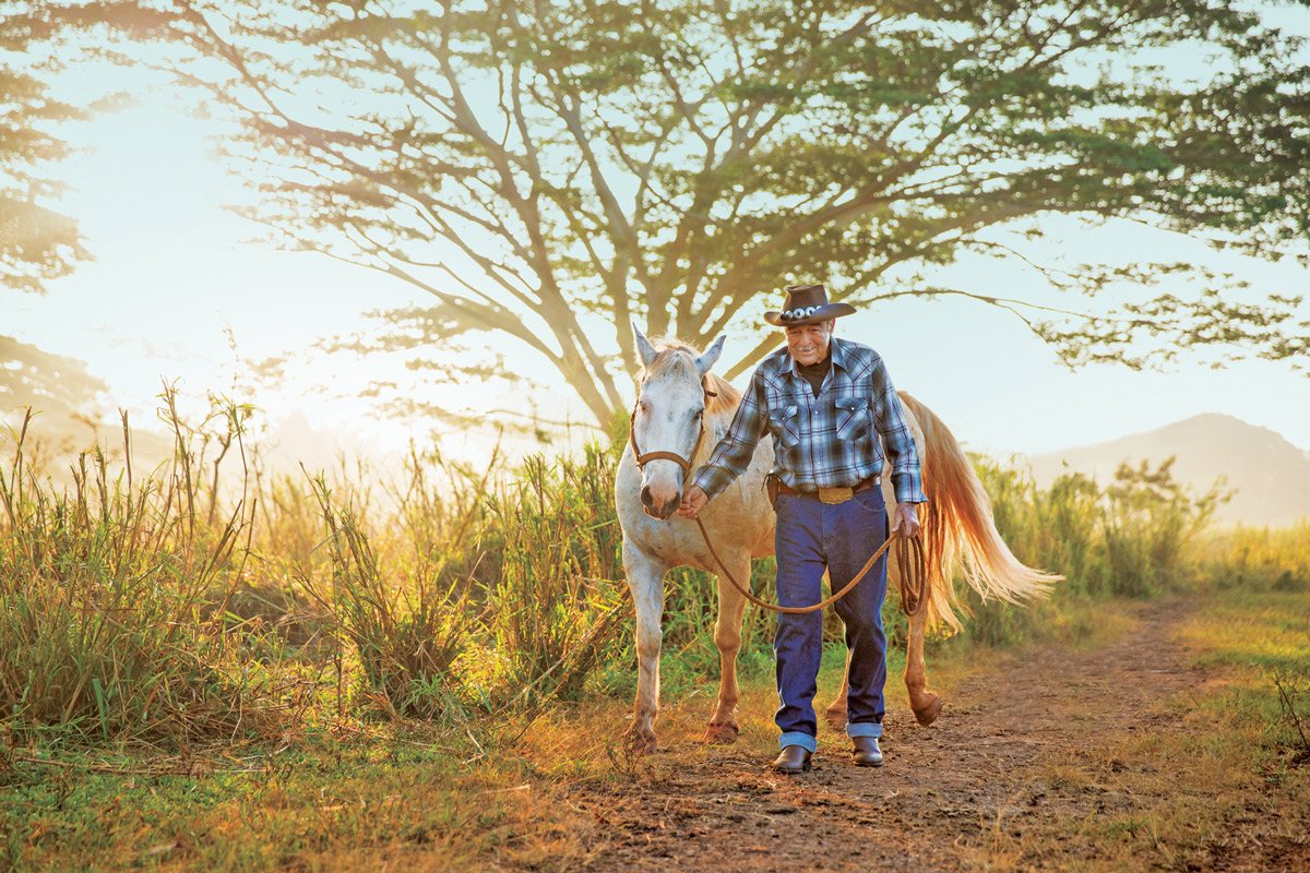 William Martin walking his horse on a trail on Kauai