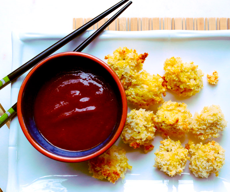 A pair of chopsticks rests on a serving dish with pieces of Tofu Katsu and a bowl of homemade Katsu Sauce