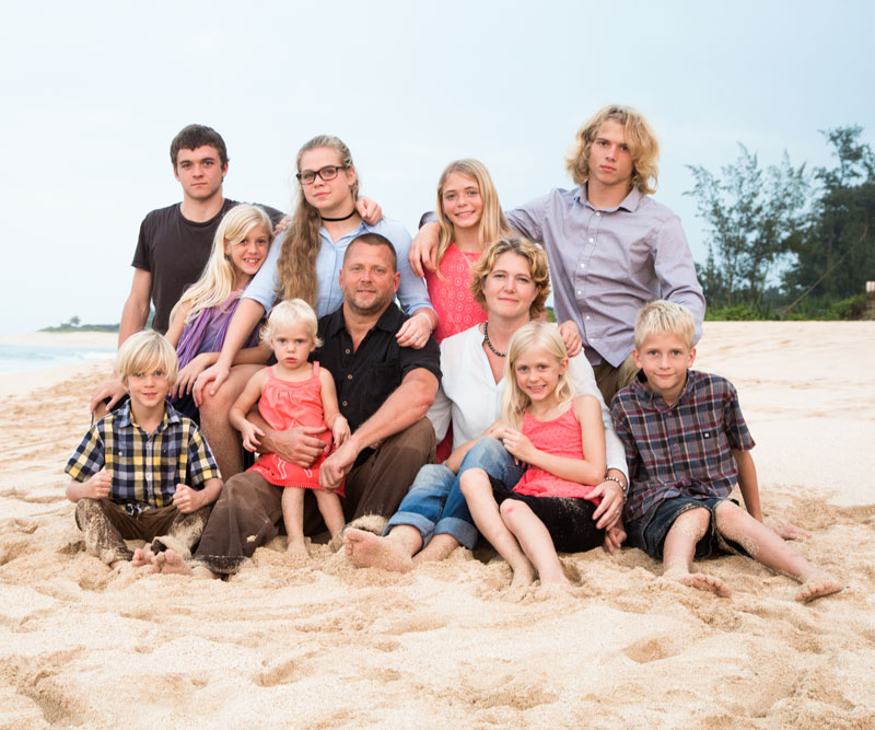 Casey Schmidt sits on a beach with her husband and nine children