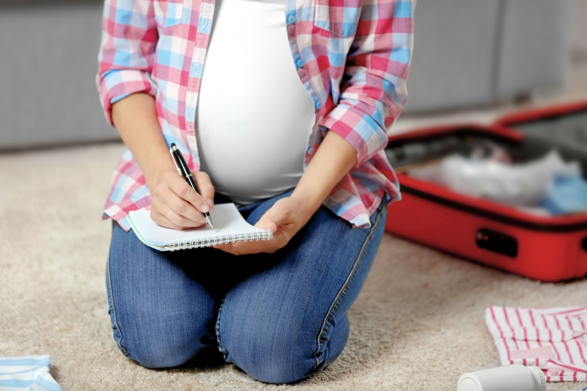 pregnant woman writing a list and packing a emergency kit