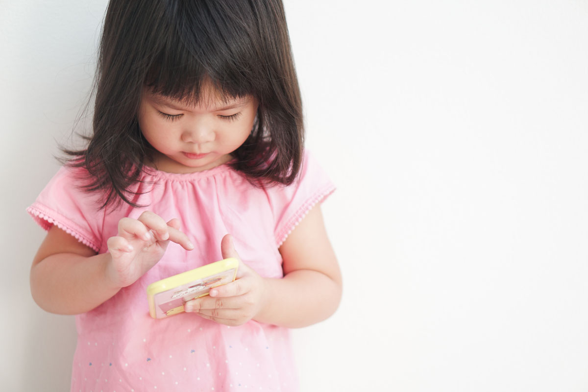 young toddler playing with games on a cell phone
