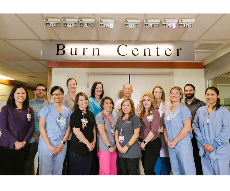 physicians and staff of the Straub Burn Unit stand in front of the office doors and sign