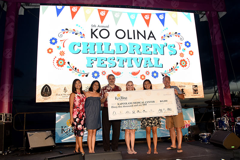 Group on stage at Ko Olina Children's Festival holding ceremonial check for $65,000