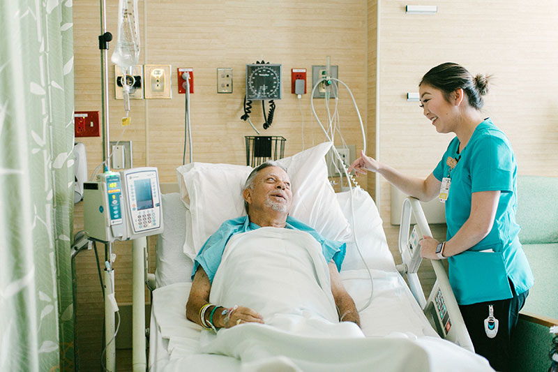 Nurse standing beside patient in hospital bed