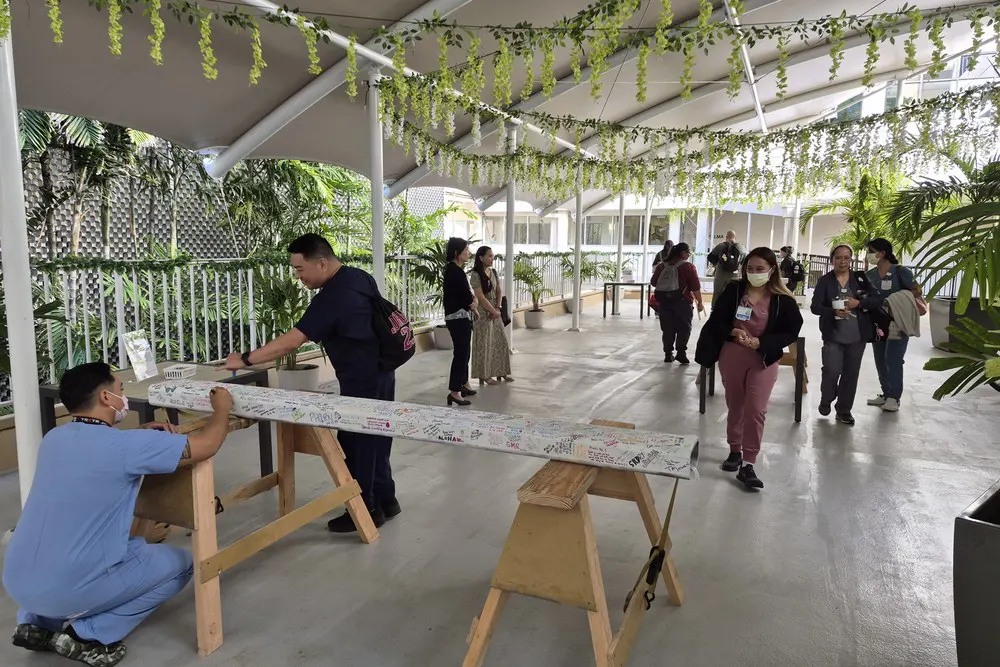 Team members sign a white construction beam in an open-air pavilion.