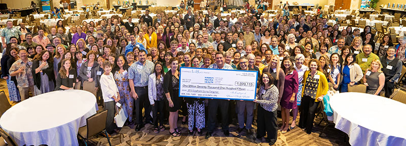 Large group of people gather around large ceremonial check