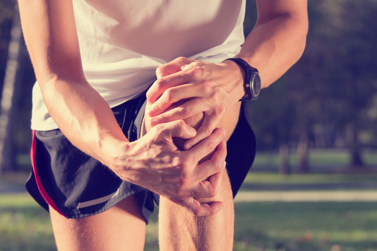 close-up of a male runner grabbing his knee in pain