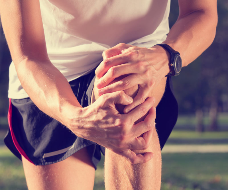 close-up of a male runner grabbing his knee in pain