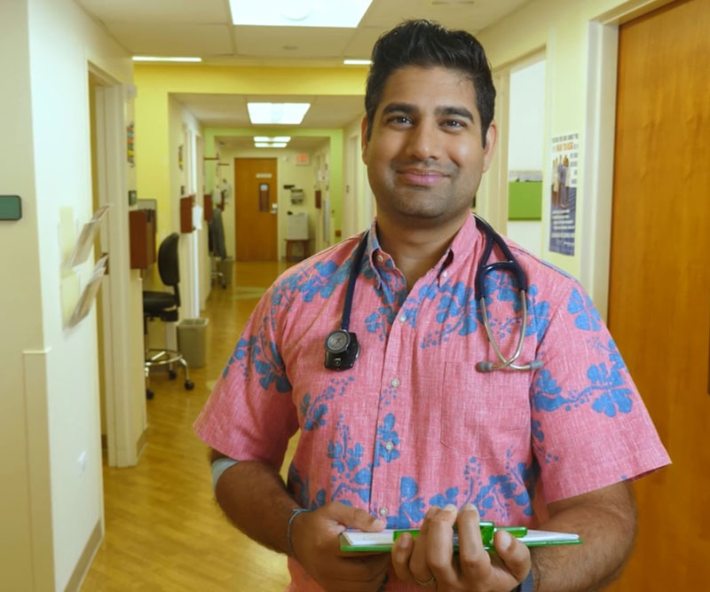 A smiling Dr. Amar Kapur stands in the hall of the Straub Clinic at Kailua