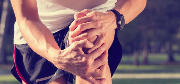 close-up of a male runner grabbing his knee in pain