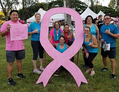 Hawaii Pacific Health employees at the Susan G. Komen Race for the Cure standing behind a huge pink ribbon
