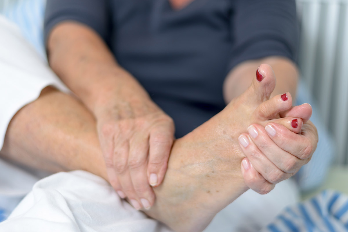 older woman examines the bottom of her foot