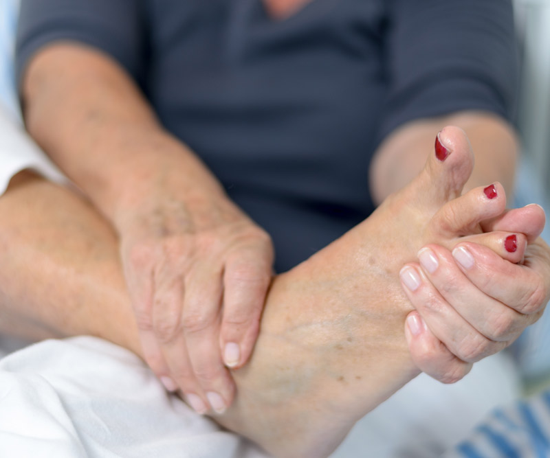 older woman examines the bottom of her foot