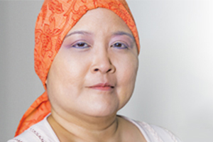 headshot of a women with an orange bandanna who received cancer care