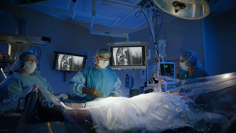 Physician and nurses in masks and scrubs in operating room