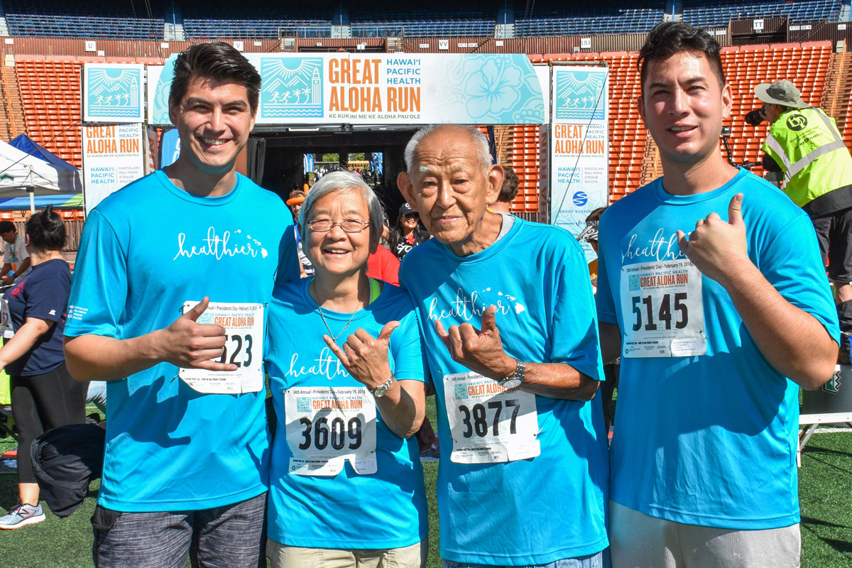man, daughter and two grown grandsons wave a shaka at the finish line of the Great Aloha Run
