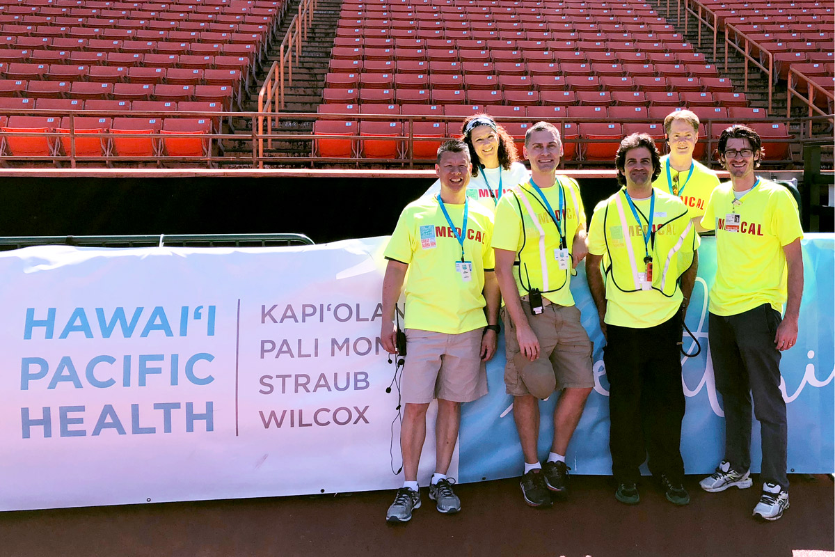 Medical volunteers stand in front of a Hawaii Pacific Health banner at the Great Aloha Run finish at Aloha Stadium