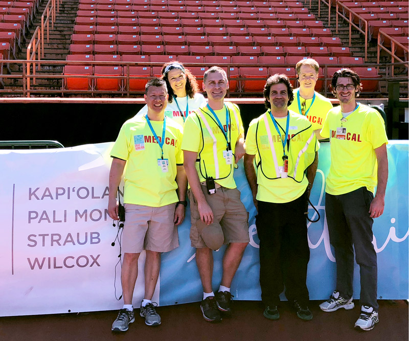 Medical volunteers stand in front of a Hawaii Pacific Health banner at the Great Aloha Run finish at Aloha Stadium