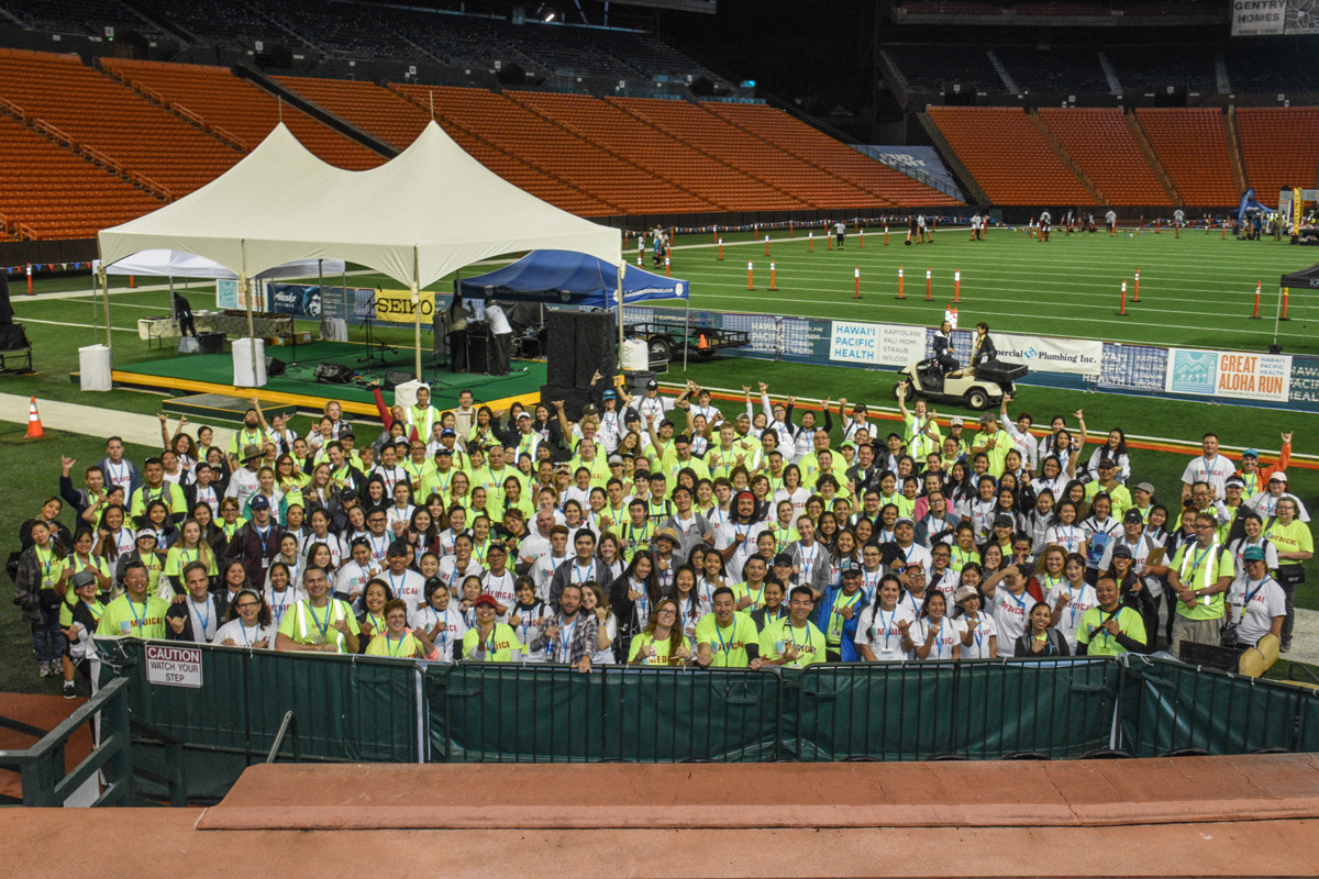 Volunteers gather on the field of Aloha Stadium for a safety brief before the start of the Great Aloha Run