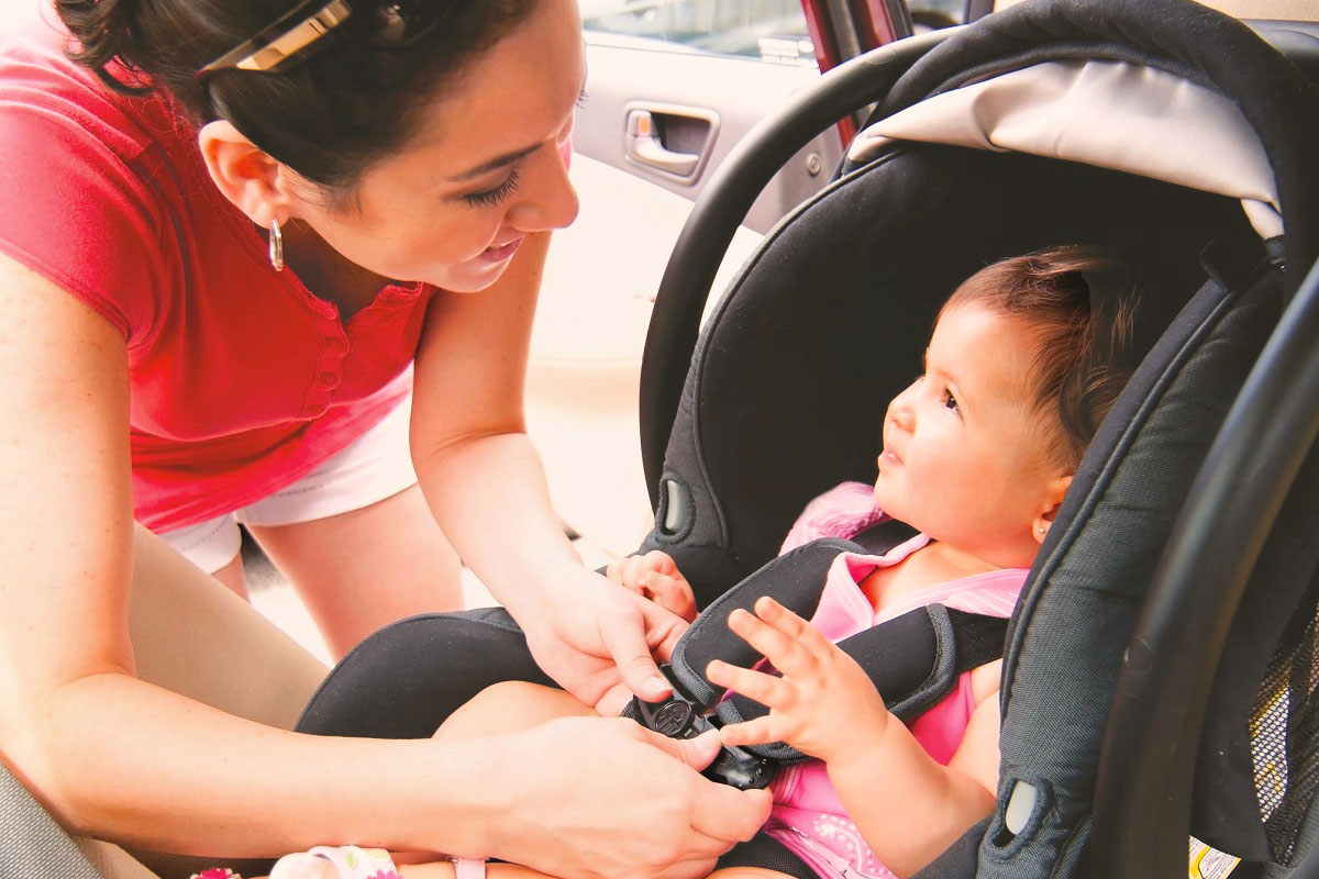 a women securing child safety seat