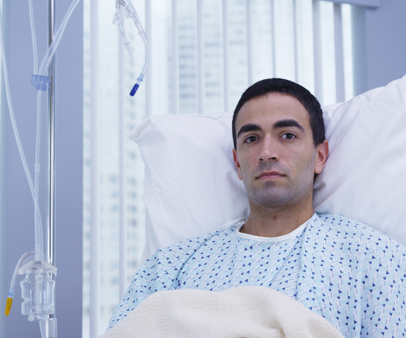 A young man in a hospital bed intensely stares directly into the camera