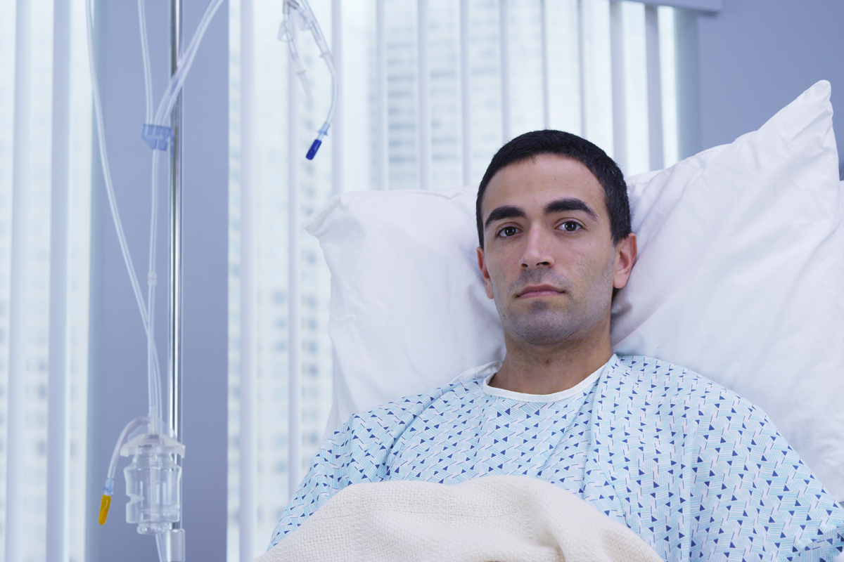 A young man in a hospital bed intensely stares directly into the camera