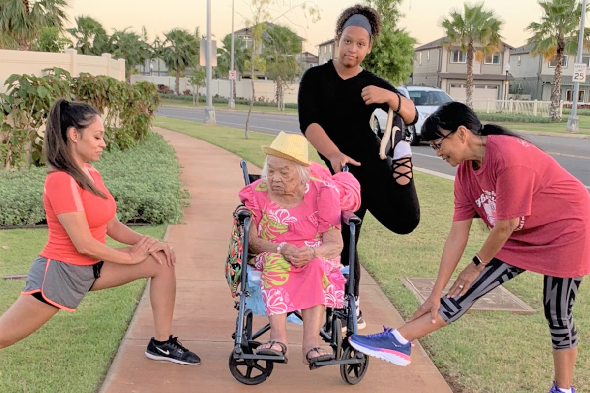 Relana, Carlina, Anaia and Menia stretch on a sidewalk during a training walk around a well-manicured neighborhood