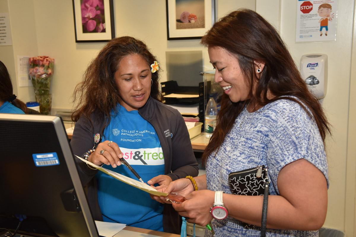 Aida Corpuz (right) reviews paperwork prior to receiving free cervical cancer and breast cancer screenings at the Kapiolani Women's Center as part of an event put on through a grant from College of American Pathologists (CAP) Foundation's See, Test & Treat program.