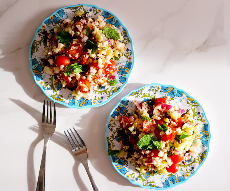 two colorful plates of Summer Tabbouleh on a marble counter top next to two forks