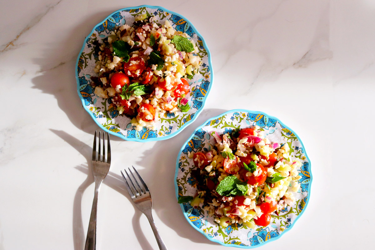 two colorful plates of Summer Tabbouleh on a marble counter top next to two forks